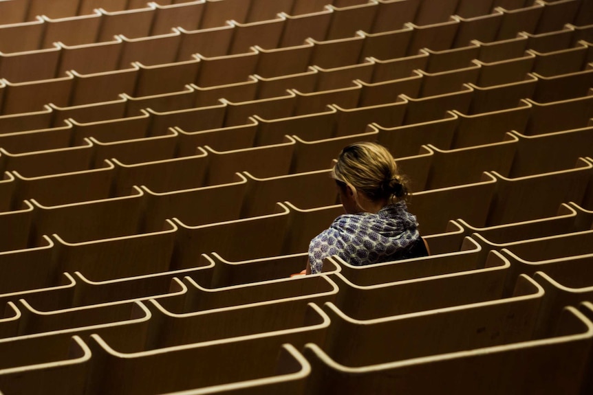 A woman sits in the Sydney Opera House Concert Hall