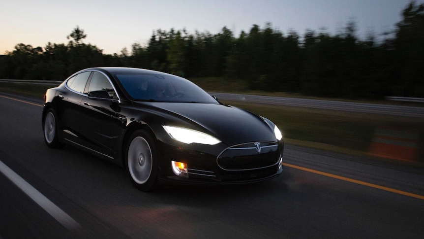 A black Tesla car driving at dusk