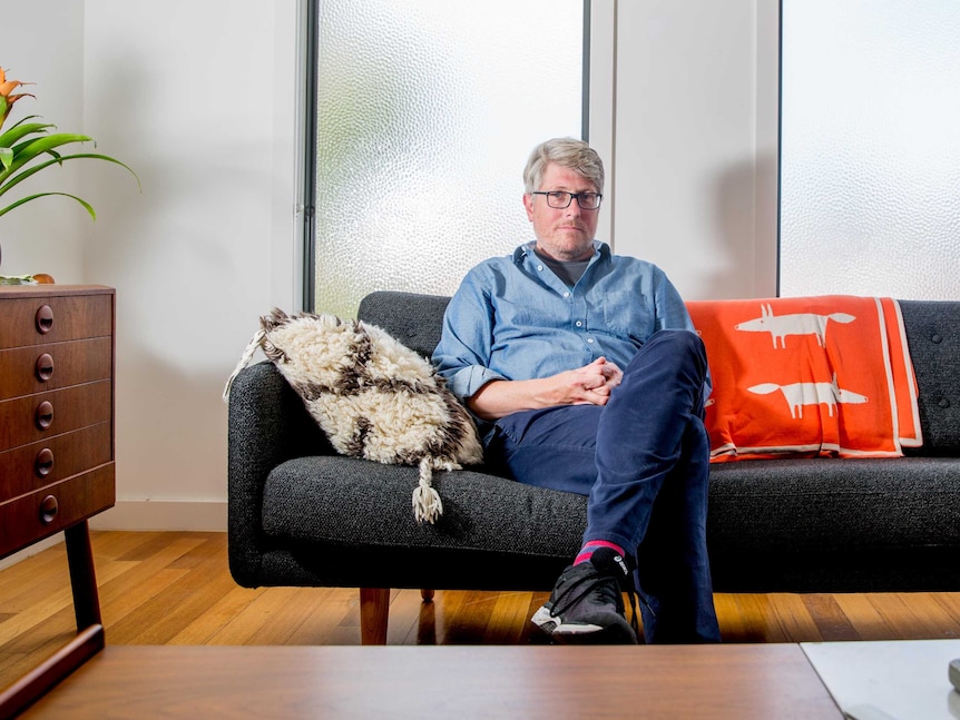 A portrait of Chris sitting on his couch