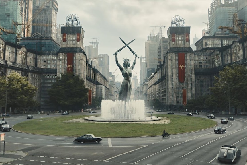 A scene that resembles Nazi Germany with an imposing statue of a woman with two swords crossed above her head.