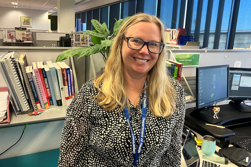 Jennie Haarsager stands in an office, wearing a spotted shirt