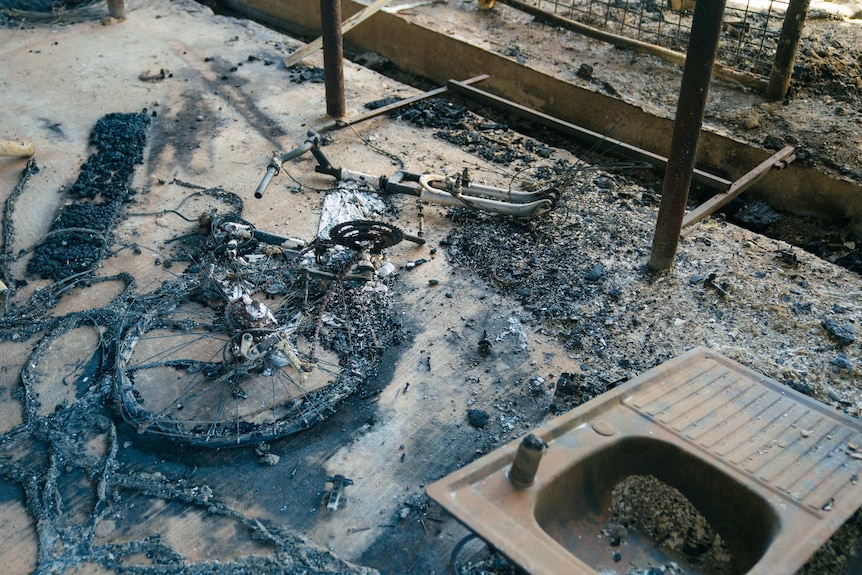 The remains of a bike which melted on the ground. The wheel is just a charred circle.