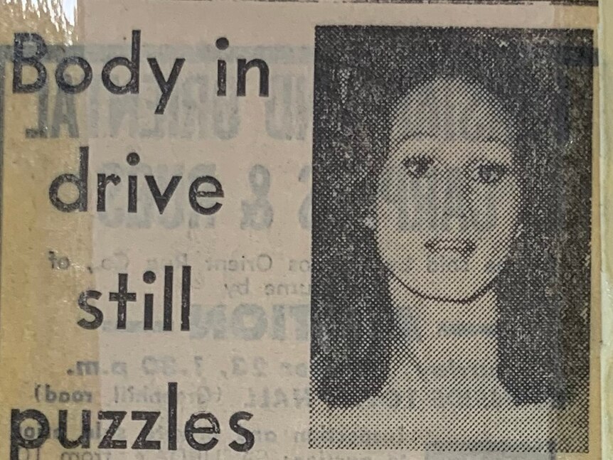 A newspaper clipping with the headline 'body in drive still puzzles' with a photo of Lisa Tane-Baker.