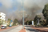 Thick black smoke rises into the sky from a bushfire at the end of a road in Joondalup.