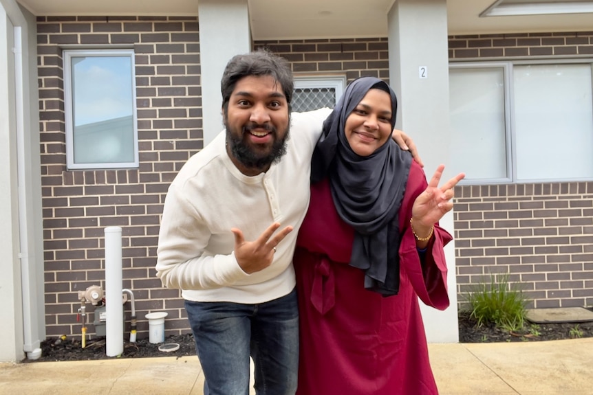 Seeni and Shameina stand playfully in front of house