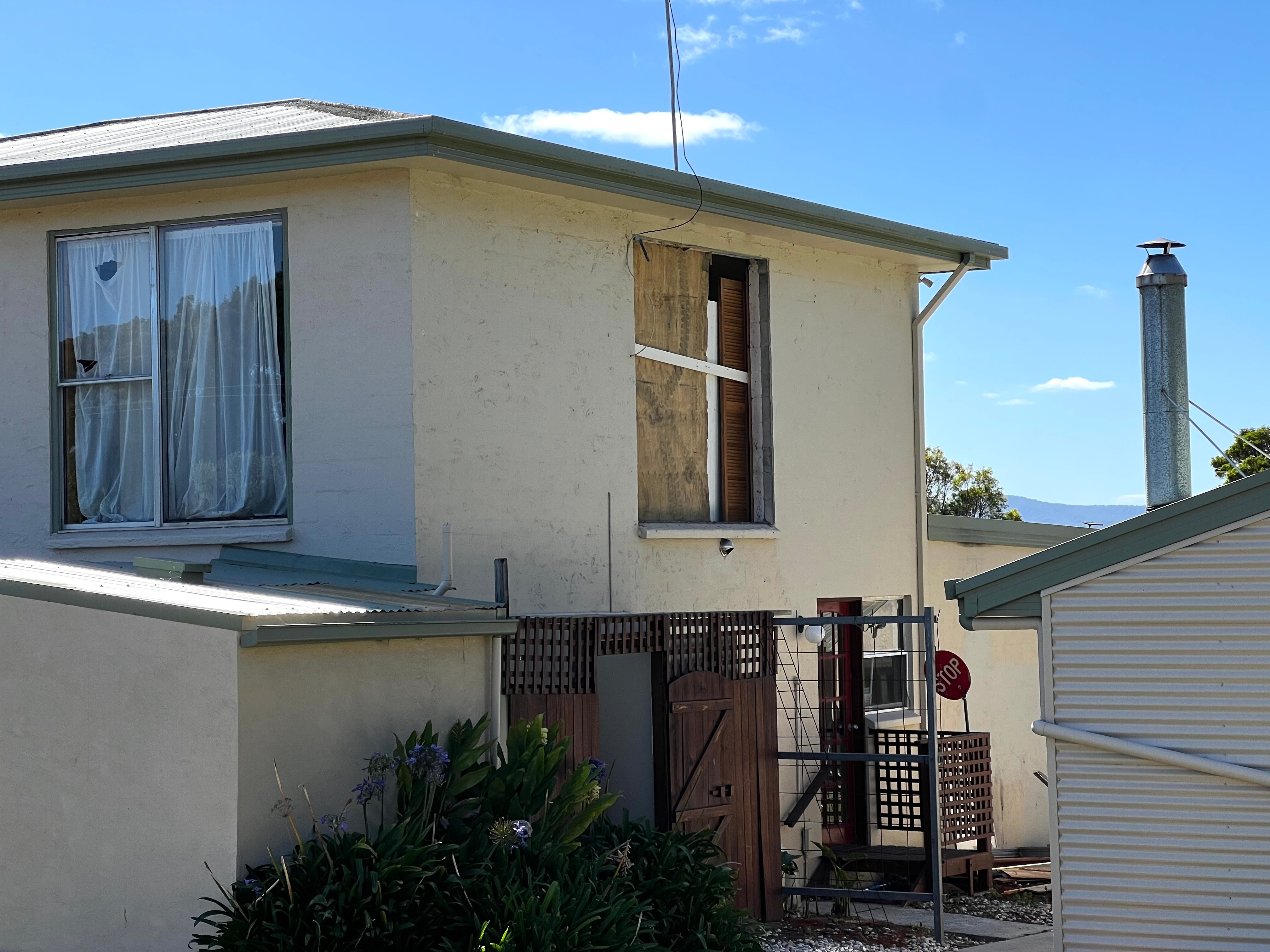 A run-down house is seen here. Curtains hang in the windows.