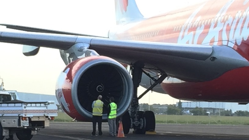 Airport staff inspect the right engine of the  AirAsia X plane on the runway