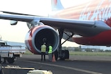 Airport staff inspect the right engine of the  AirAsia X plane on the runway