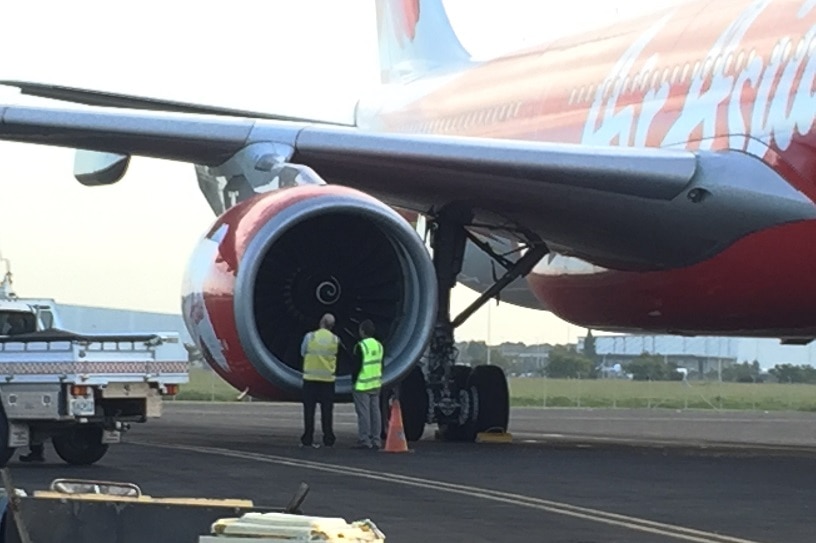 Airport staff inspect the right engine of the  AirAsia X plane on the runway