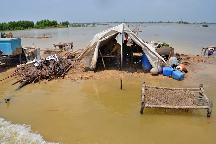 A makeshift tent sits in flood waters as a family takes shelter inside.