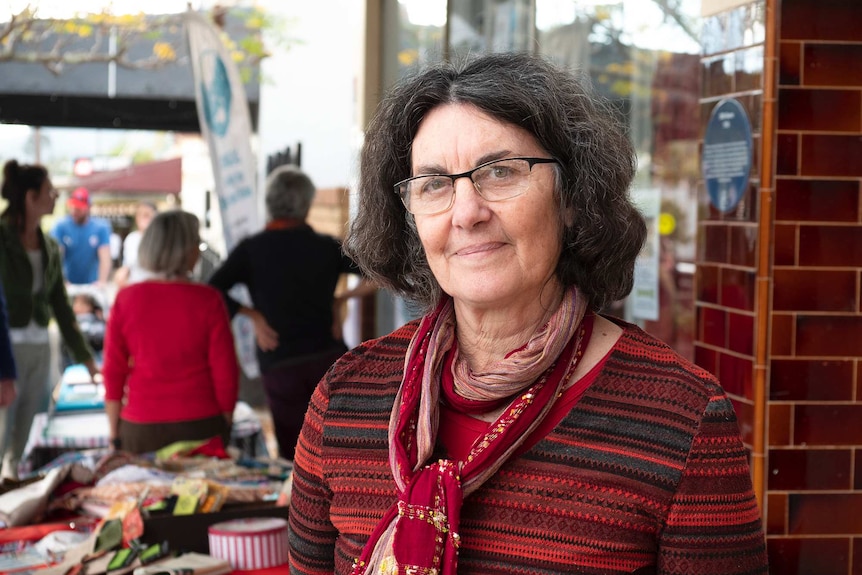 A woman with dark wavy hair in a striped red knit jumper