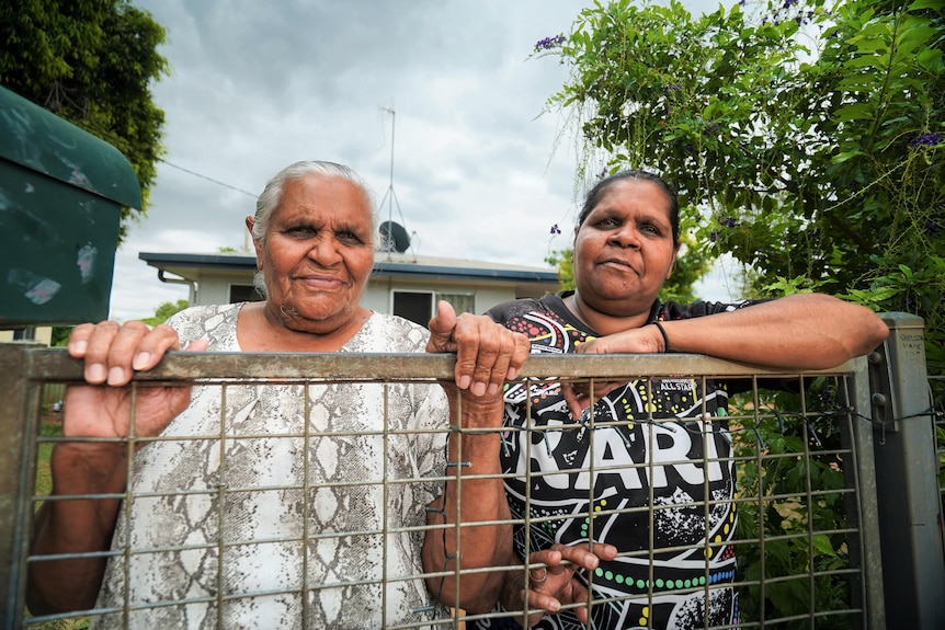 Older woman and younger woman standing near fence