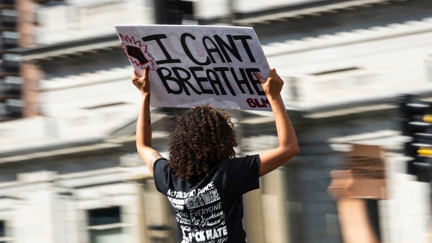 A person holds a sign as a crowd marches through downtown to protest the death of George Floyd.