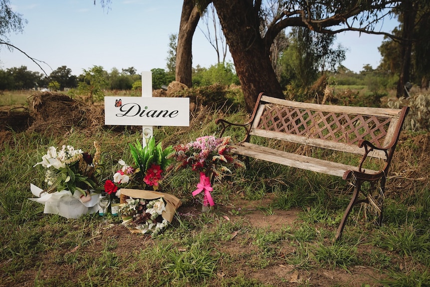 A chair surrounded by flowers and a cross.