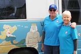 Mike and Judy Kendrick stand next to their caravan that is painted with a seascape