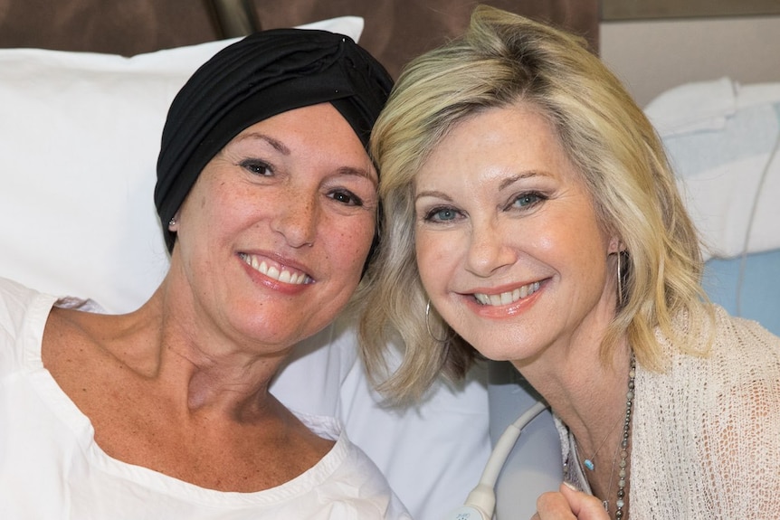 Suzi and Olivia Newton-John are smiling at the camera in hospital.