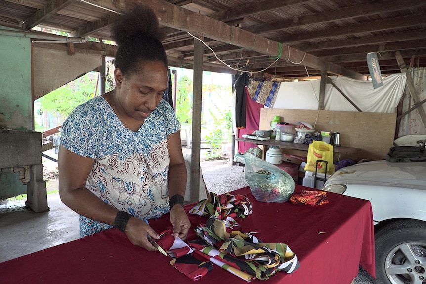 Seamstress Dulcie Maliaki cuts strips of fabric at her home in Port Moresby.