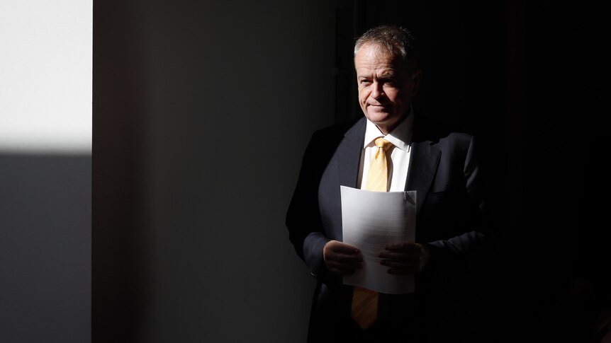 Shorten is holding papers as the light hits him in the corridor