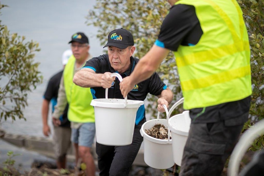 Craig Copeland in a human chain passing over buckets of cleaned oyster shells.