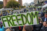 A white poster that has green text stating 'Freedom' in front of police.