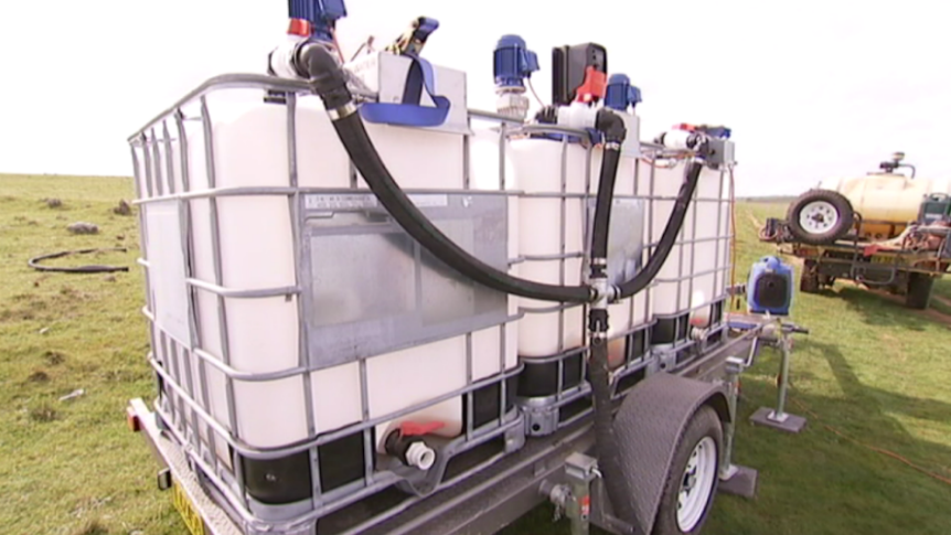 Three 1,000 litre water containers on a trailer with pipes coming off it.