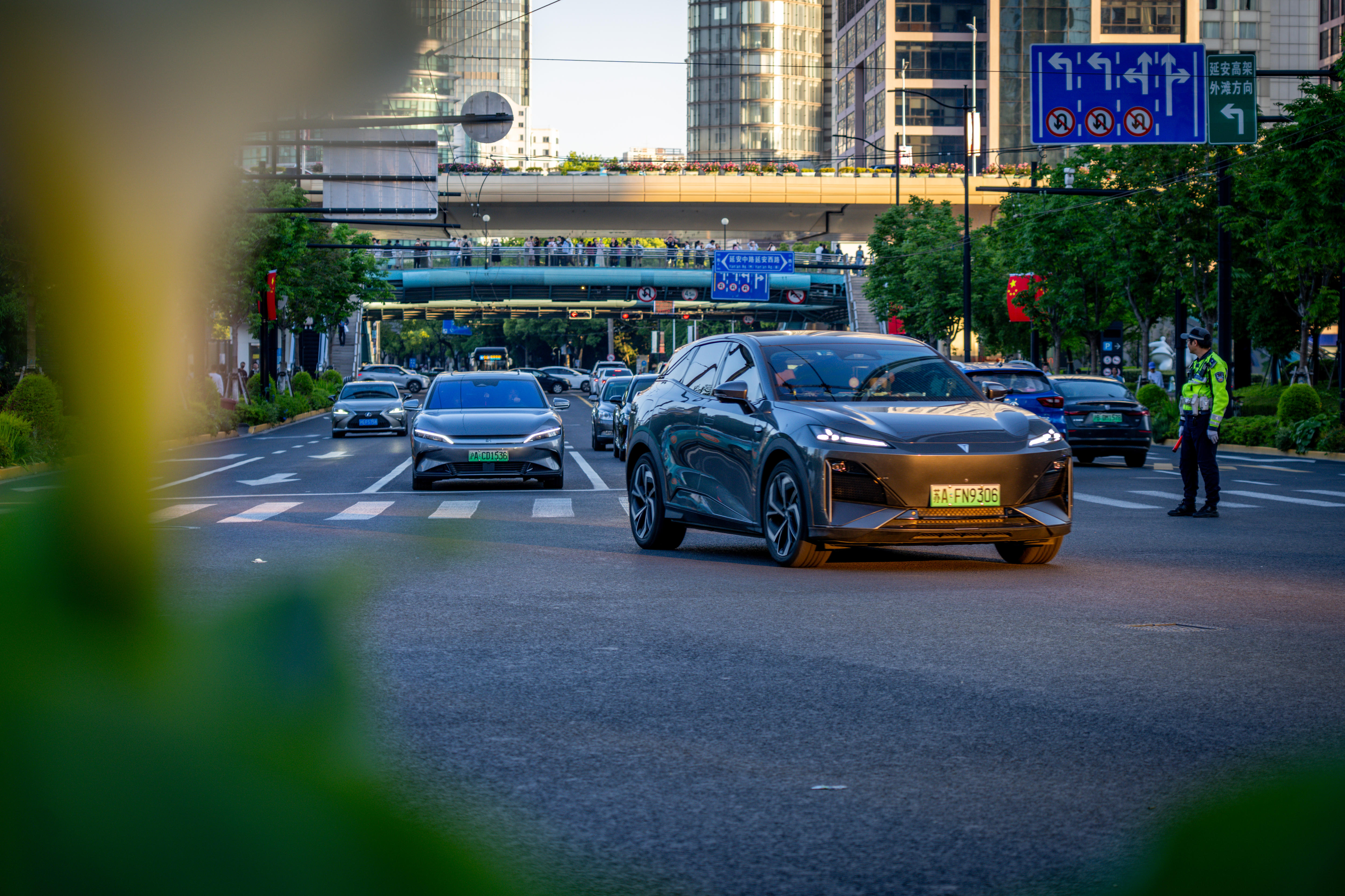 A car driving on a road with a green number plate, surrounded by other cars.