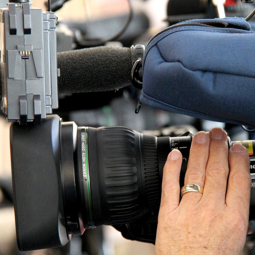 Tight shot of a man filming through a television news camera.