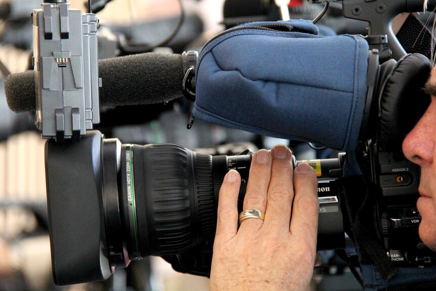 A TV camera operator adjusts the focus at a news job.