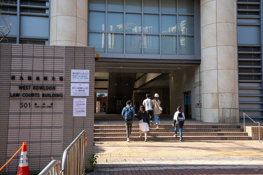Young people walk into a building marked 'West Kowloon Law Courts Building"