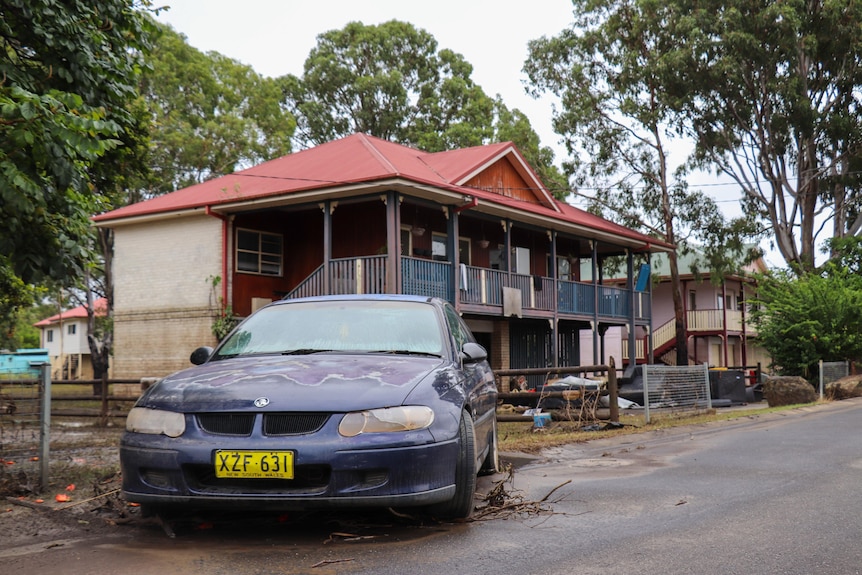 a damaged car out the front of a house