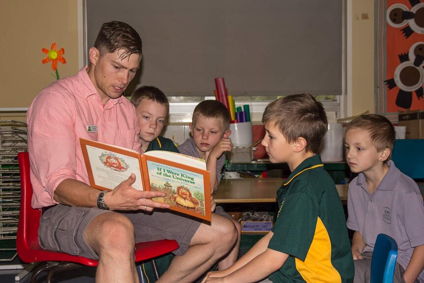A man reading a story to four boys