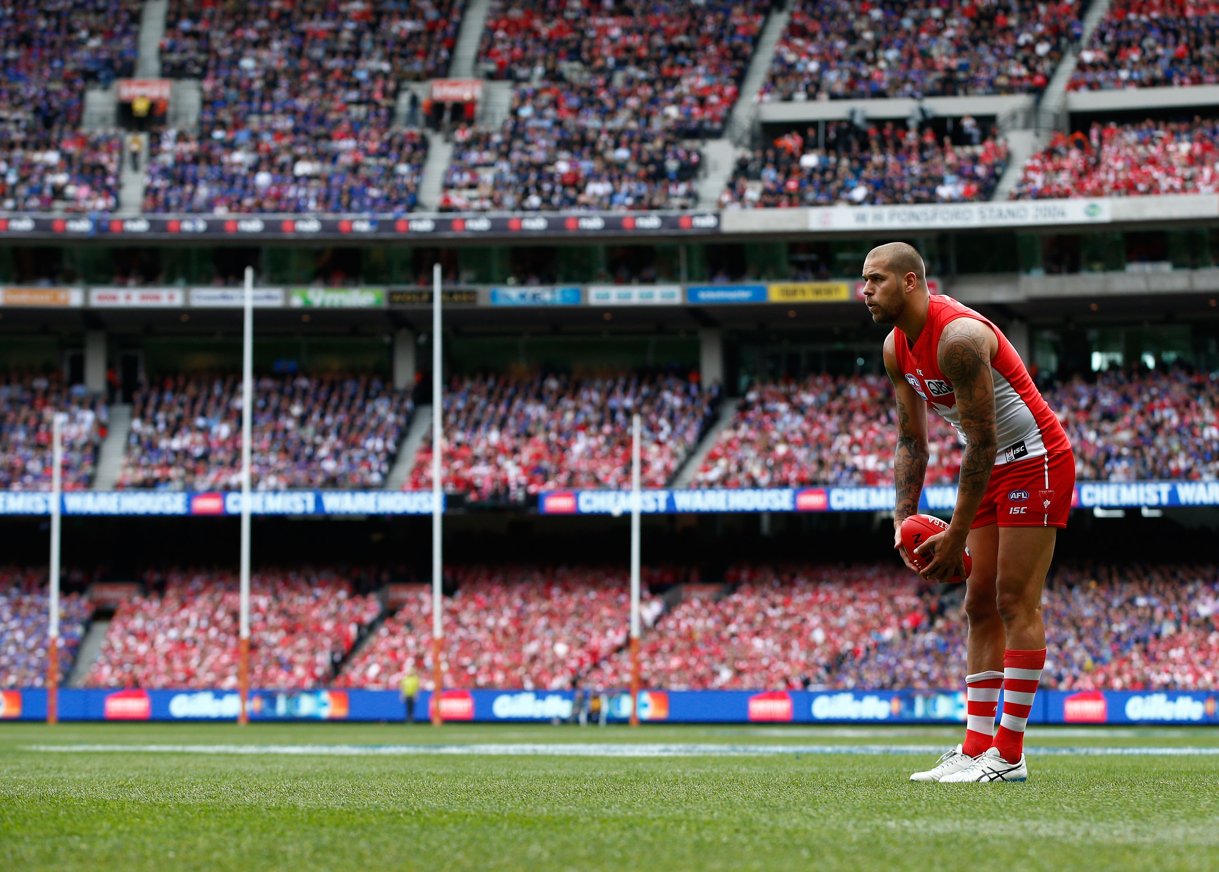 Sydney AFL star Lance Franklin holds the ball in his hands as he stands looking towards goal, about to take a kick. 