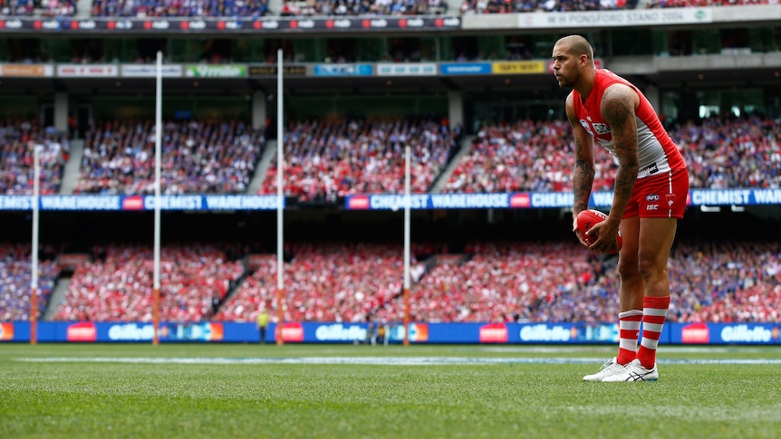 Sydney AFL star Lance Franklin holds the ball in his hands as he stands looking towards goal, about to take a kick. 