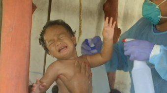 A child gets sprayed with water in Samoa during a deadly measles outbreak.
