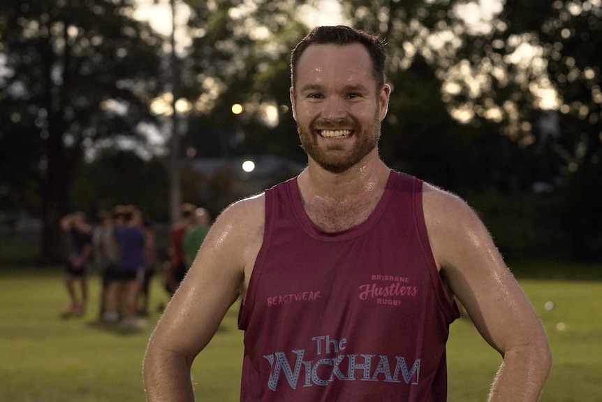 A man wearing a singlet smiles.