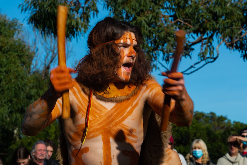 A young man with ochre body paint doing traditional Aboriginal dance.