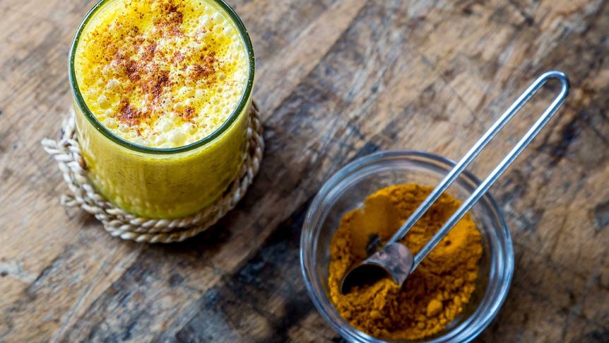 A yellow-coloured latte in a glass on a table