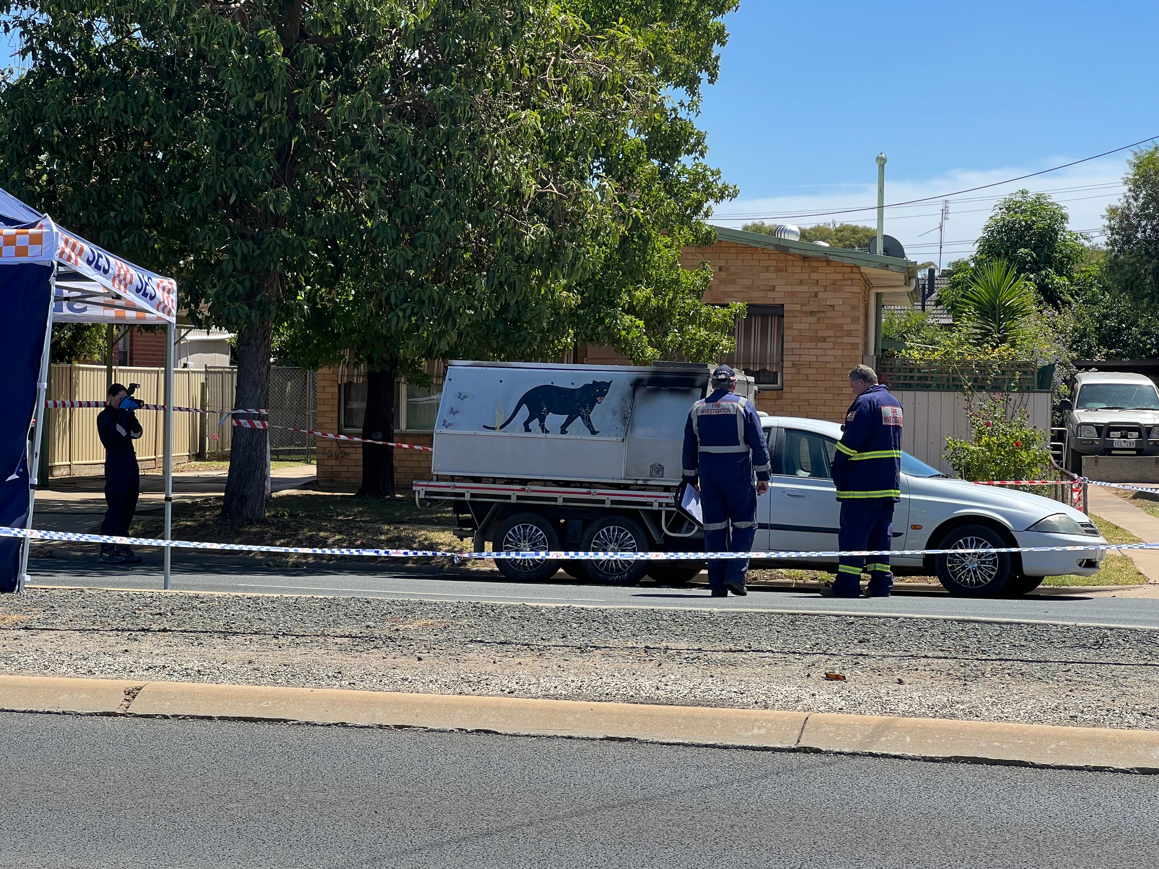 a photo of two firefightersi in front of a white ute with canopy, can see burnt patch on canopy