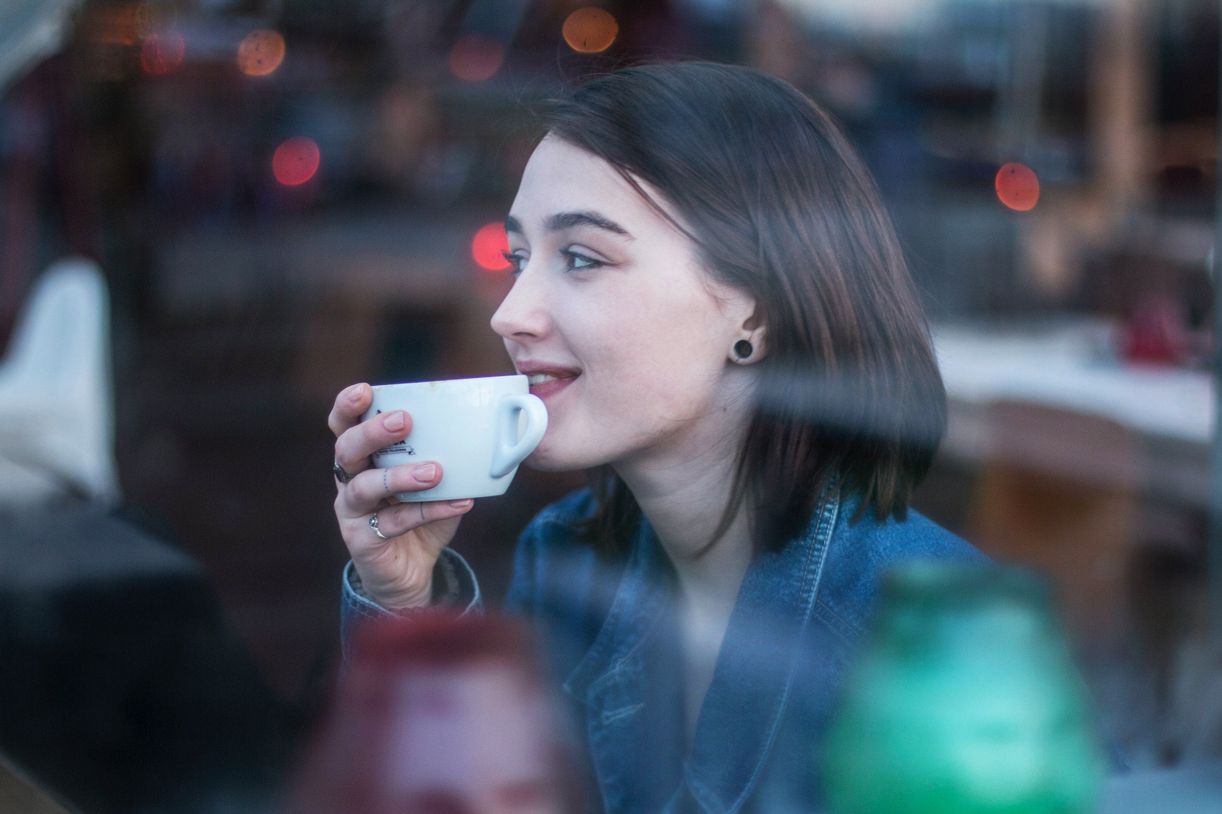 Woman sits and enjoys a coffee, in a story about the guilt of changing hairdressers or coffee shops.