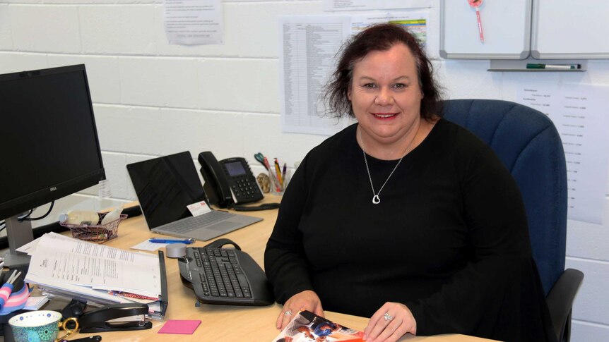 Carers ACT's Lisa Kelly sits at her desk, holding the carers strategy paperwork