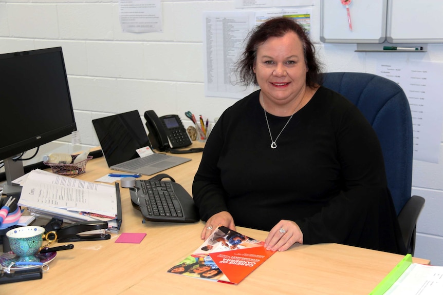 Carers ACT's Lisa Kelly sits at her desk, holding the carers strategy paperwork