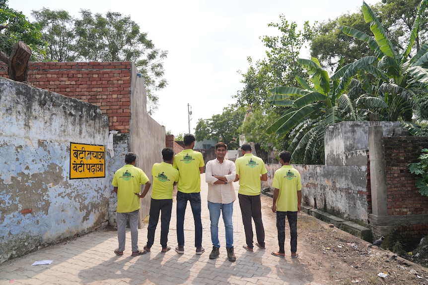 Ramveer Tanwar stands with a group of people wearing yellow shirts with "pondman" written on them.