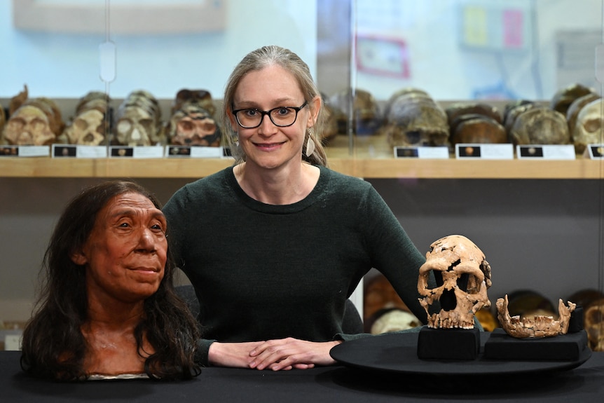 A woman smiles next to a skull.