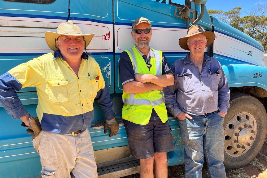 Mark Rogan, Ian Bennett and Ian Hastings standing with a grain truck in the background