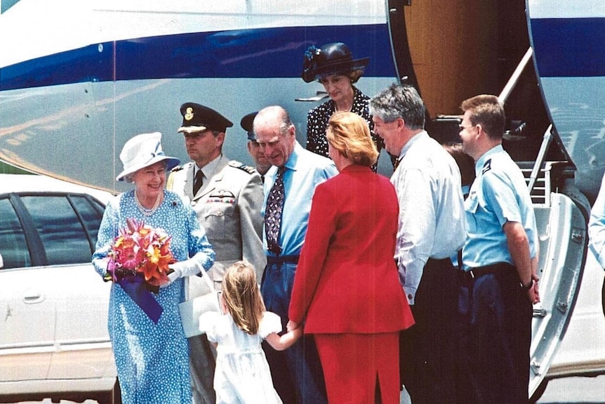 Люди, включая королеву Елизавету и принца Филиппа, собираются в передней части самолета.