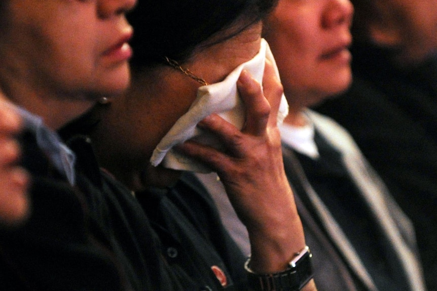 A mourner grieves during a memorial service for the victims of the Quakers Hill nursing home fire.