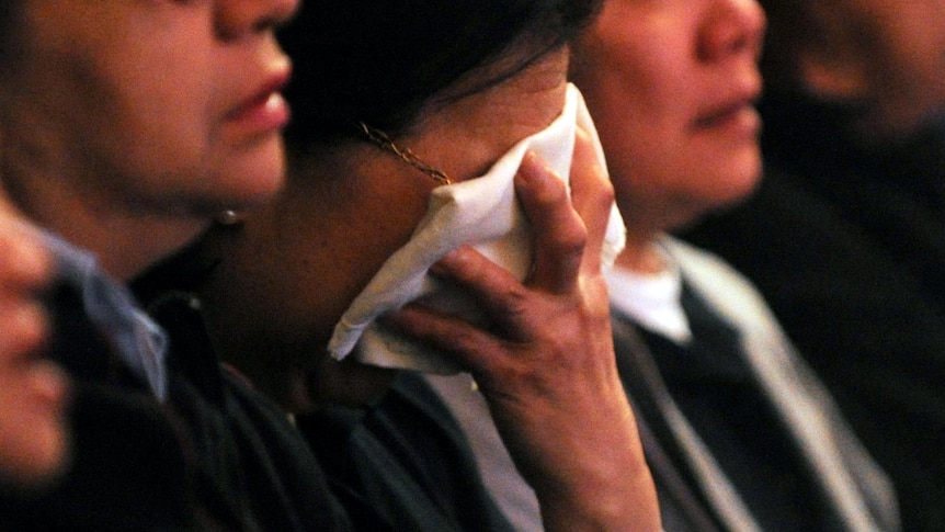 A mourner grieves during a memorial service for the victims of the Quakers Hill nursing home fire.