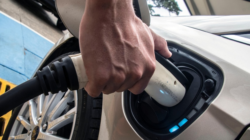 A man charges an electric vehicle