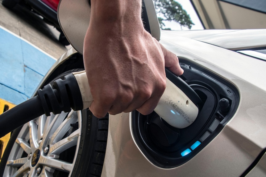 A man charges an electric vehicle