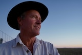 Man in cowboy hat with sunset in background